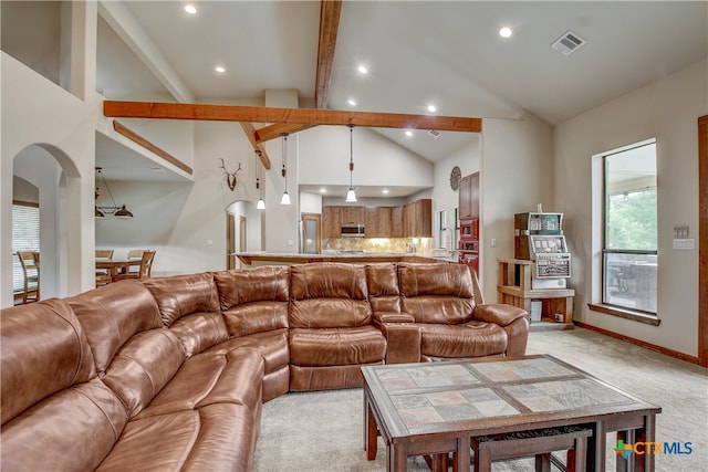 carpeted living room with high vaulted ceiling and beamed ceiling