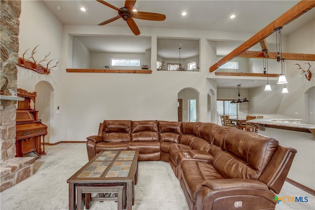 carpeted living room with a towering ceiling, ceiling fan, and a wealth of natural light