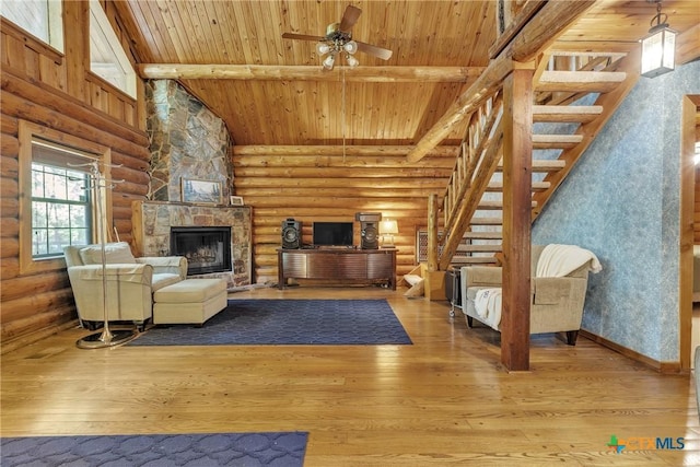 2662 Edgegrove, Canyon Lake, TX 78133 - unfurnished living room with log walls, stairway, a wood ceiling with exposed beams, a stone fireplace, and hardwood / wood-style flooring