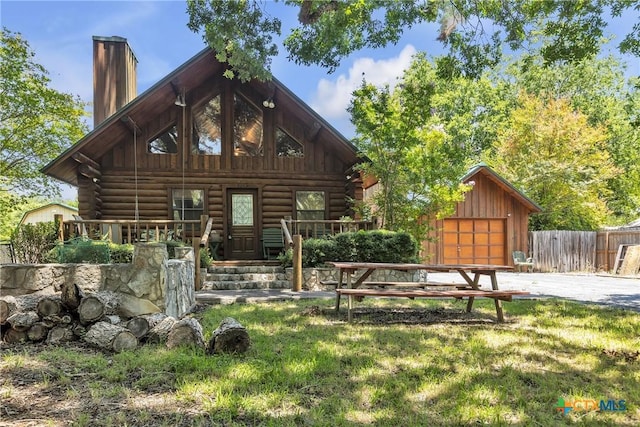 2662 Edgegrove, Canyon Lake, TX 78133 - back of property featuring log siding, a chimney, an outbuilding, driveway, and covered porch