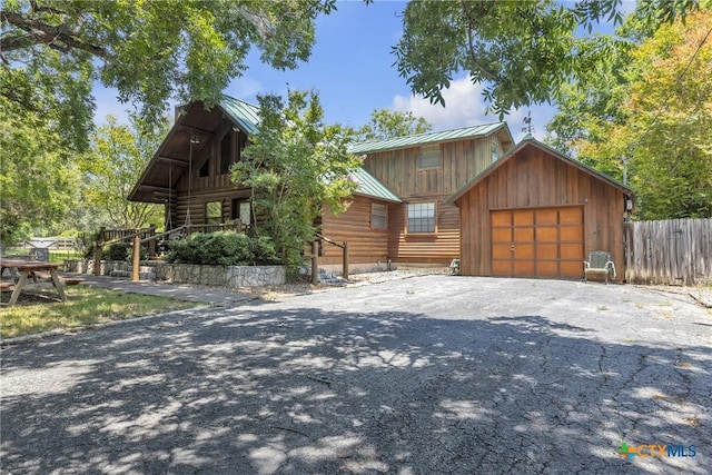 2662 Edgegrove, Canyon Lake, TX 78133 - view of front of home featuring a metal roof, log exterior, driveway, an attached garage, and a standing seam roof