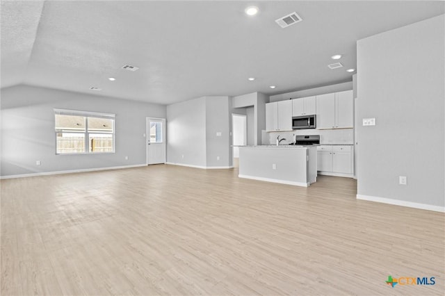 9063 Rancher Trl, Seguin, TX 78155 - unfurnished living room featuring light wood-style flooring, recessed lighting, baseboards, and lofted ceiling