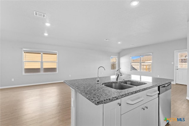 9063 Rancher Trl, Seguin, TX 78155 - kitchen featuring stainless steel dishwasher, a sink, a center island with sink, light wood finished floors, and white cabinetry