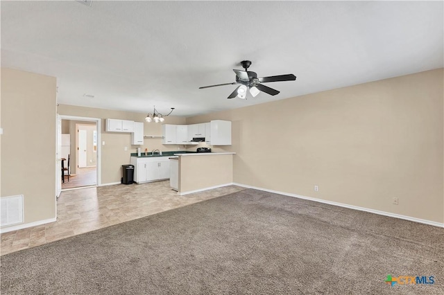 unfurnished living room featuring visible vents, light carpet, ceiling fan with notable chandelier, a sink, and baseboards