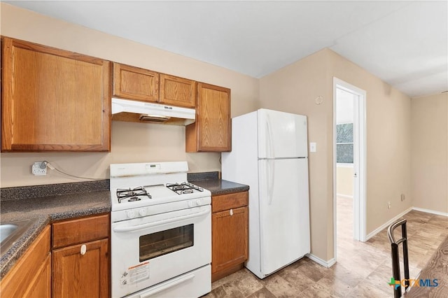 kitchen with dark countertops, baseboards, under cabinet range hood, brown cabinetry, and white appliances