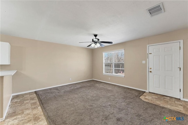 foyer entrance with visible vents, light carpet, baseboards, and ceiling fan