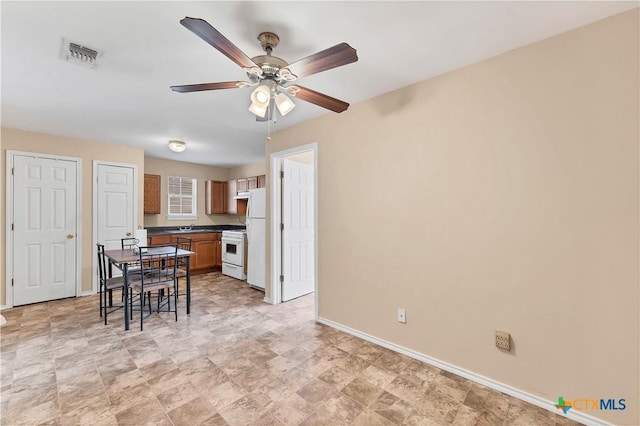 kitchen featuring white appliances, a ceiling fan, baseboards, visible vents, and dark countertops