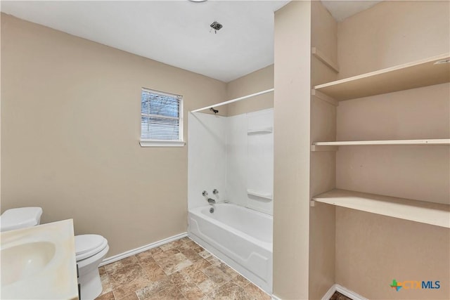 full bath featuring stone finish flooring, baseboards, toilet, vanity, and  shower combination