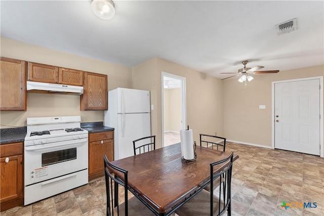 kitchen featuring dark countertops, visible vents, under cabinet range hood, brown cabinets, and white appliances