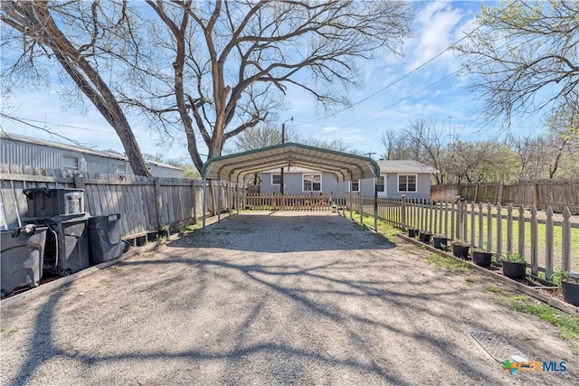 exterior space featuring a detached carport, fence private yard, and aphalt driveway