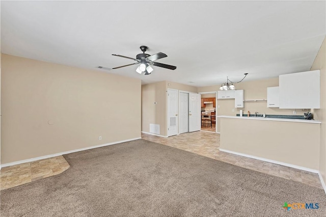 unfurnished living room featuring light carpet, visible vents, ceiling fan with notable chandelier, and baseboards