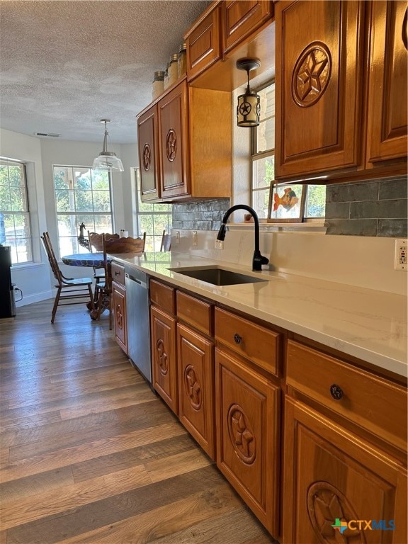 kitchen featuring dishwasher, sink, hanging light fixtures, dark wood-type flooring, and backsplash