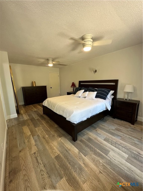 bedroom featuring ceiling fan, hardwood / wood-style floors, and a textured ceiling