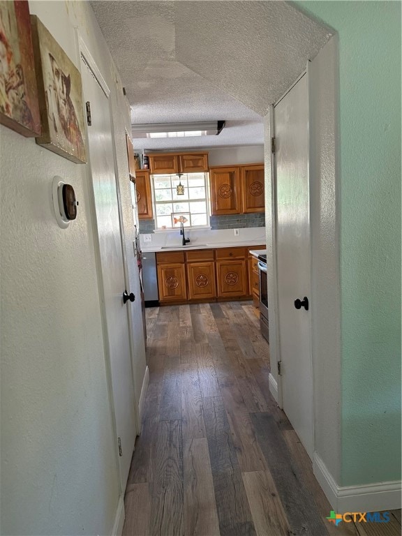 hallway with a textured ceiling, dark wood-type flooring, and sink