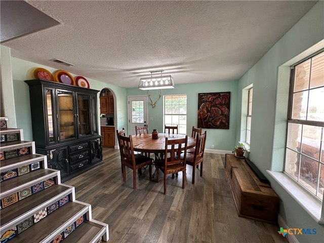 dining area with a textured ceiling and dark hardwood / wood-style floors