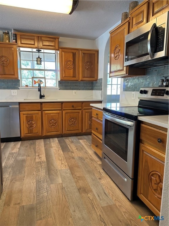 kitchen with backsplash, stainless steel appliances, light hardwood / wood-style floors, and sink