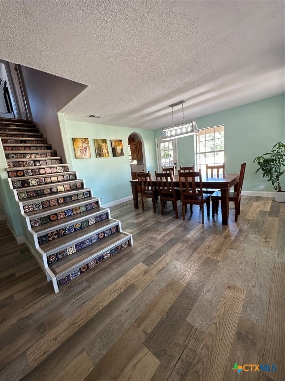 dining room with dark wood-type flooring and a textured ceiling