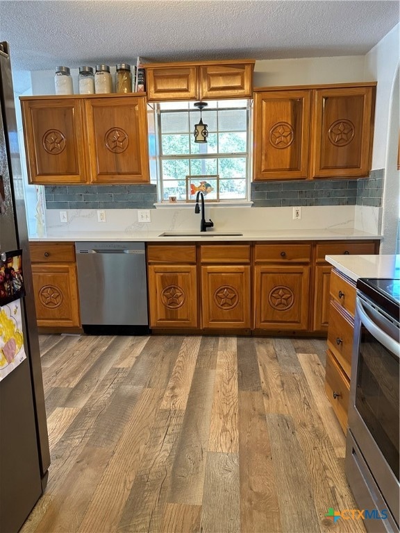 kitchen featuring appliances with stainless steel finishes, backsplash, light hardwood / wood-style flooring, and sink