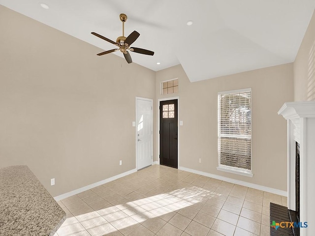 tiled living room with ceiling fan and a fireplace