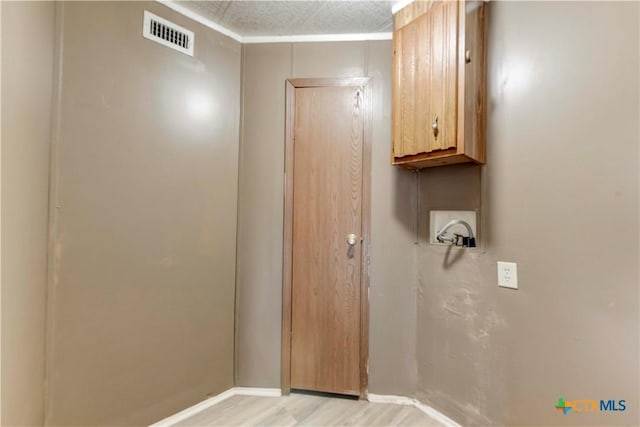 clothes washing area featuring light hardwood / wood-style floors, cabinets, and washer hookup