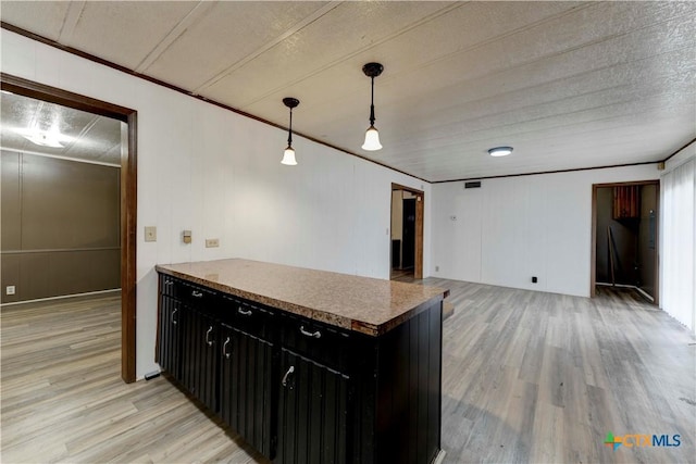 kitchen featuring light wood-type flooring, ornamental molding, and hanging light fixtures