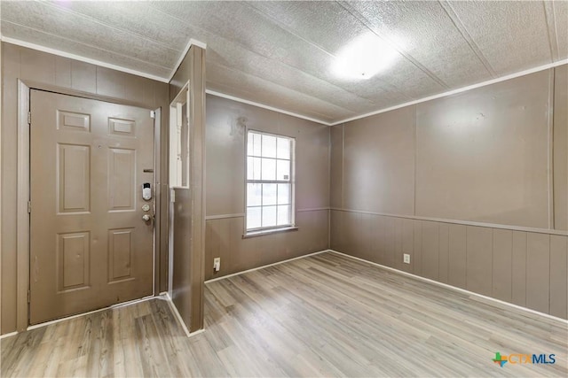 entrance foyer with ornamental molding and light hardwood / wood-style flooring