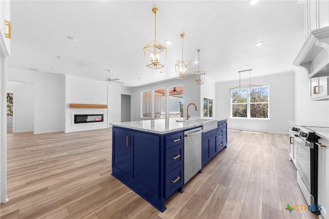 kitchen featuring blue cabinets, stainless steel appliances, a sink, ceiling fan with notable chandelier, and light countertops