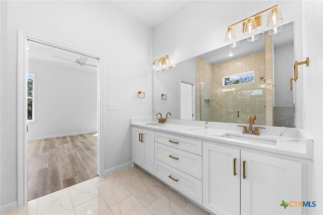 full bathroom with double vanity, a shower stall, baseboards, and a sink