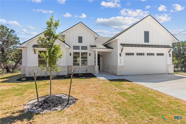modern farmhouse with concrete driveway, board and batten siding, a standing seam roof, stone siding, and a front yard