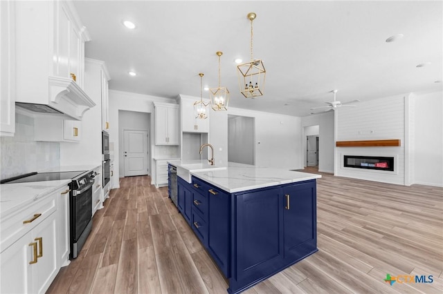 kitchen with white cabinets, a sink, light wood-style floors, blue cabinetry, and appliances with stainless steel finishes