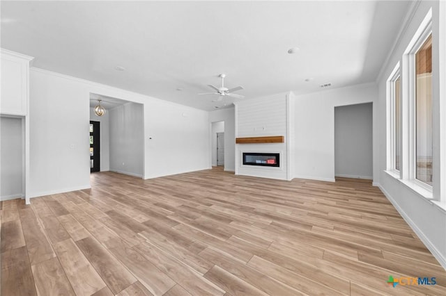 unfurnished living room with a fireplace, light wood-style floors, a wealth of natural light, and a ceiling fan