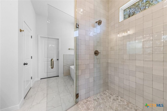 full bath with a tile shower, a soaking tub, marble finish floor, and baseboards