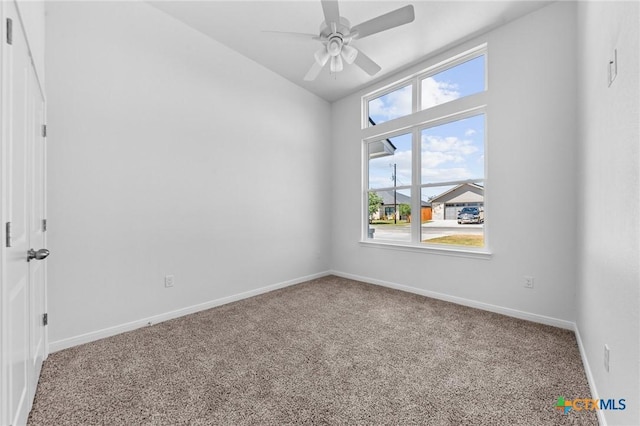 carpeted empty room with lofted ceiling, a ceiling fan, and baseboards