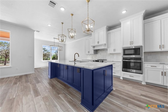 kitchen with a sink, a chandelier, blue cabinetry, appliances with stainless steel finishes, and visible vents