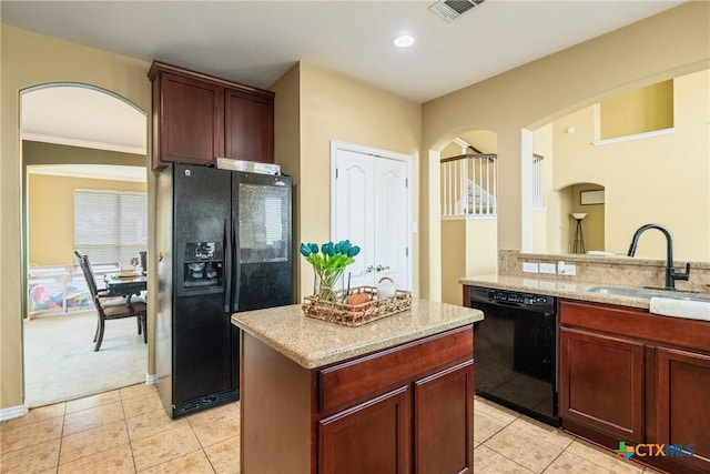 1002 Wallin Farms Cv, Hutto, TX 78634 - kitchen with black appliances, arched walkways, light stone countertops, light tile patterned floors, and recessed lighting