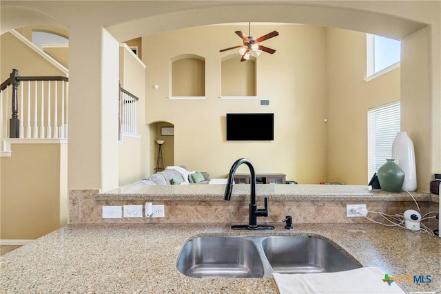1002 Wallin Farms Cv, Hutto, TX 78634 - kitchen featuring a ceiling fan, light stone countertops, open floor plan, a towering ceiling, and arched walkways