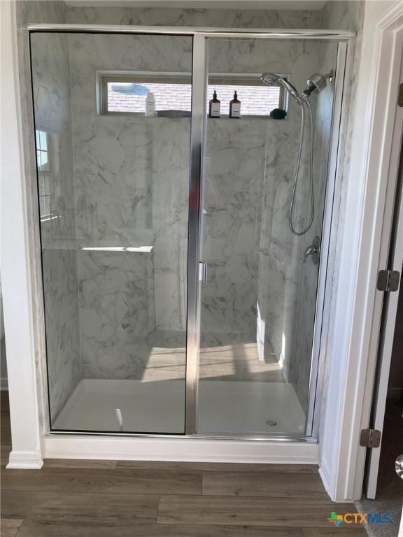 full bath featuring a marble finish shower and wood finished floors