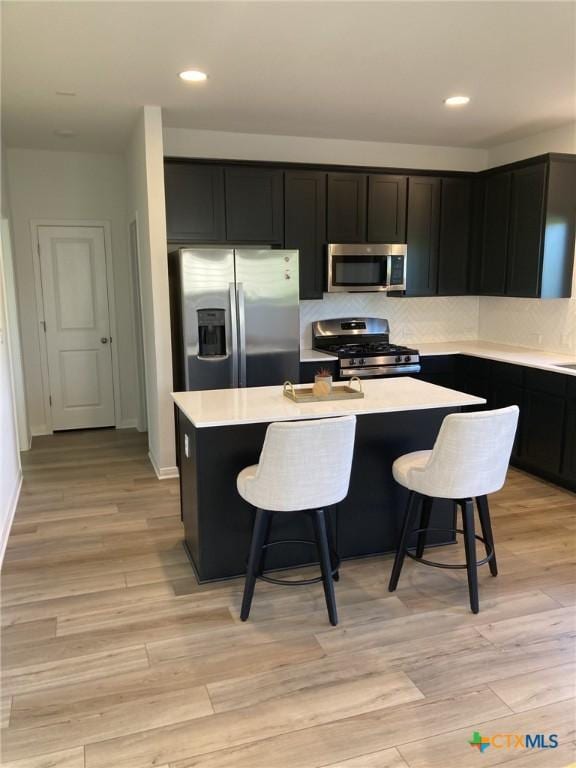 kitchen with light countertops, a kitchen island with sink, a breakfast bar area, and stainless steel appliances