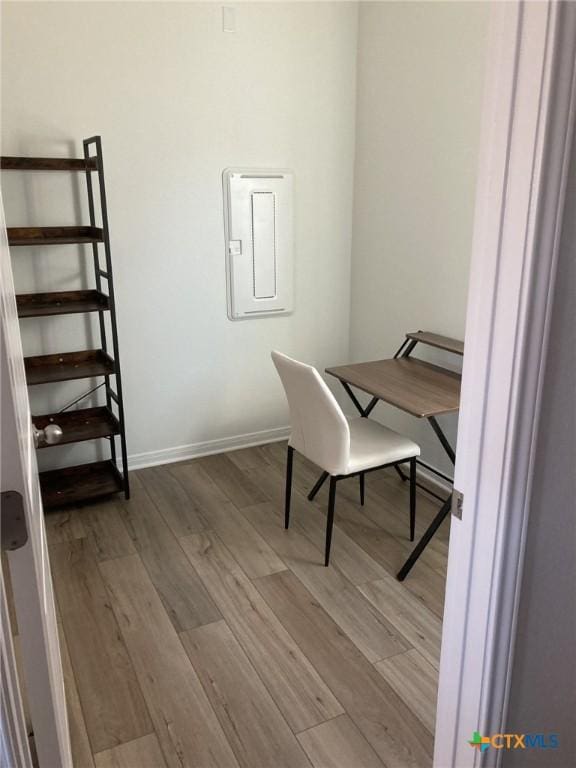 office with electric panel, baseboards, and wood finished floors