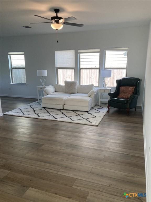 living room featuring wood finished floors, baseboards, a ceiling fan, and visible vents
