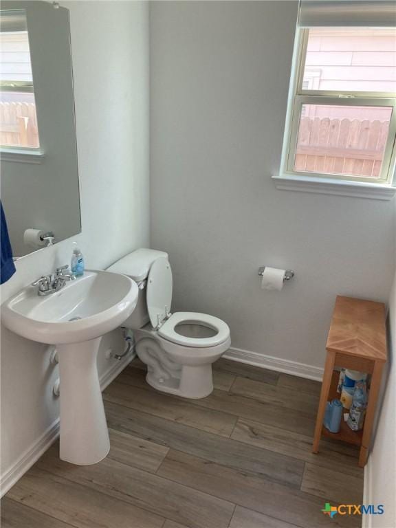 bathroom with toilet, wood finished floors, and baseboards