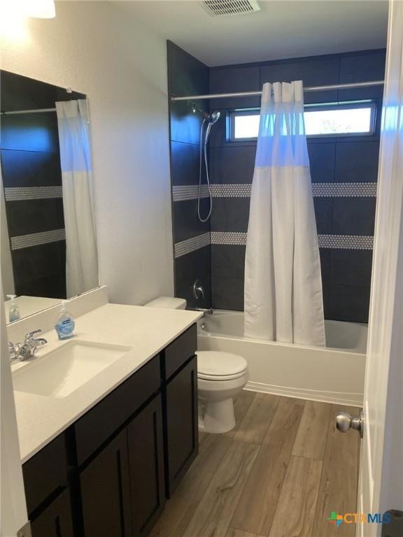 bathroom with vanity, shower / bath combination with curtain, toilet, visible vents, and wood finished floors