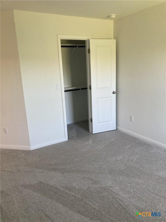 unfurnished bedroom featuring a closet, baseboards, and carpet floors