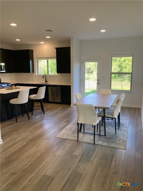 dining area featuring light wood-style flooring, a healthy amount of sunlight, visible vents, and recessed lighting