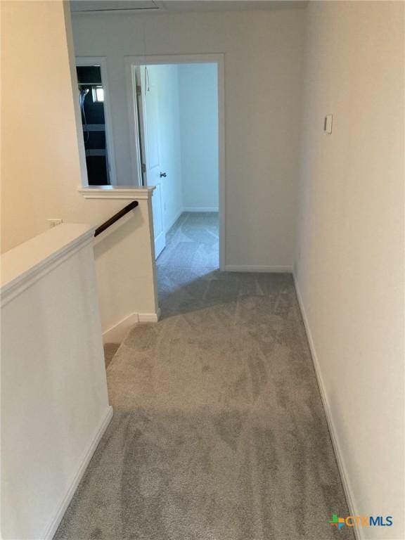 corridor featuring carpet flooring, baseboards, attic access, and an upstairs landing