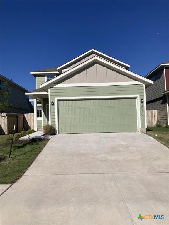 view of front of property featuring an attached garage, driveway, and fence
