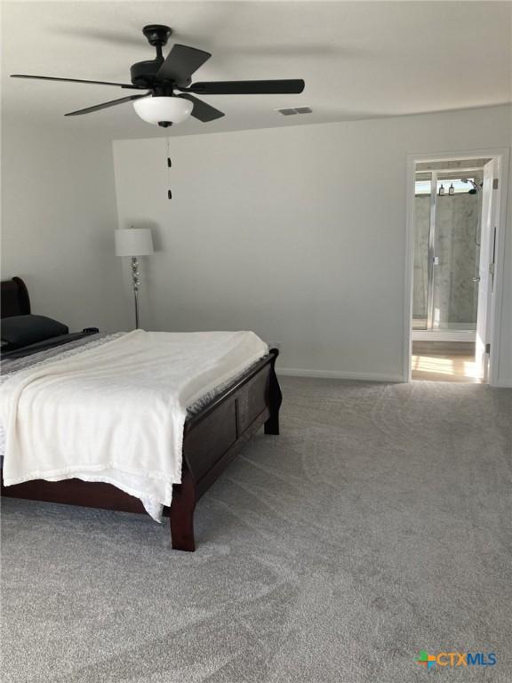 carpeted bedroom featuring ensuite bath, visible vents, baseboards, and a ceiling fan