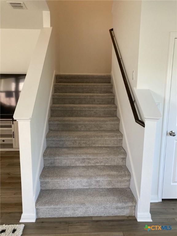 stairs with wood finished floors, baseboards, and visible vents