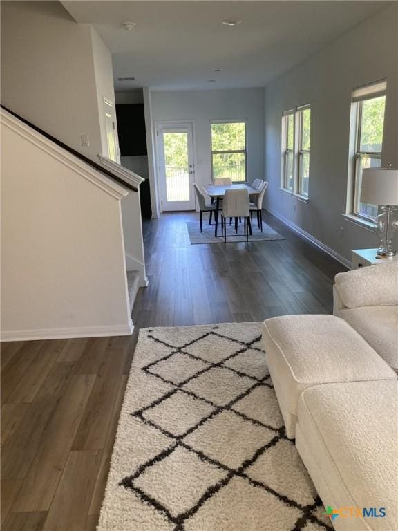 living area with wood finished floors, baseboards, and stairway