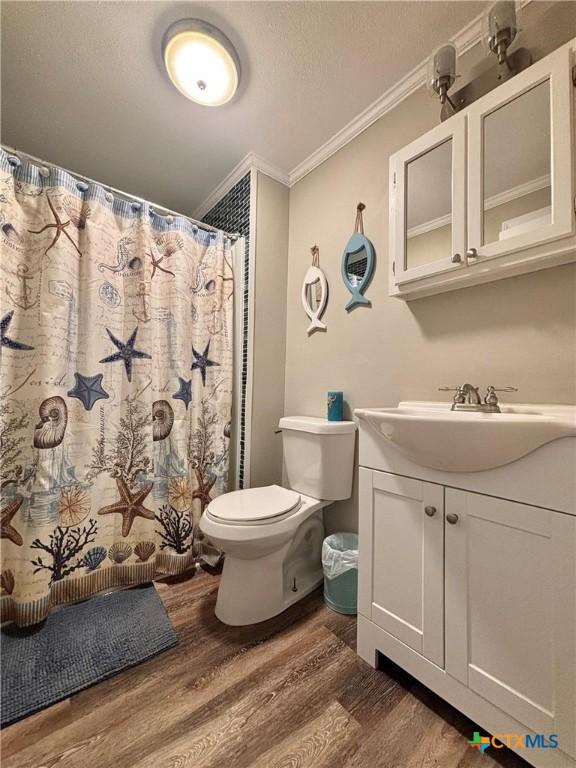 1403 Bill Tindall Ave, Seadrift, TX 77983 - full bath featuring ornamental molding, wood finished floors, toilet, vanity, and a shower with shower curtain
